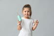© Pixel-Shot - Cute little girl with oral irrigator and dental floss on grey background