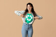 © Pixel-Shot - Beautiful young African-American woman pointing at t-shirt with recycling symbol on brown background