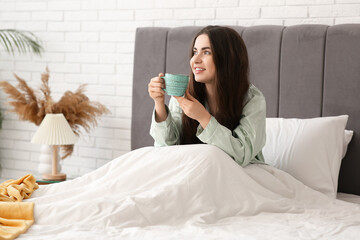 Canvas Print - Pretty young woman with cup of tea lying in cozy bed