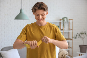 Wall Mural - Young man peeling banana at home