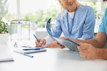 Poster - Mature doctors studying MRI scan at table in clinic, closeup