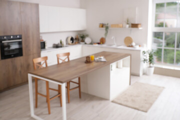 Wall Mural - Blurred view of light kitchen with counters, table and plants