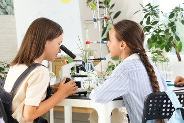 Sticker - Teenage girl looking through microscope in Biology class at school, back view