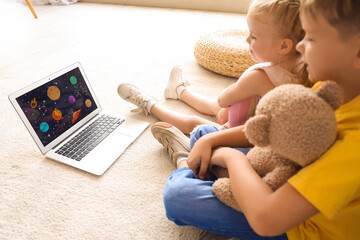 Wall Mural - Cute little children watching cartoons on laptop at home