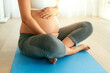 © TamJam/peopleimages.com - Yoga, pregnant woman and hands on stomach in home for healthy exercise, wellness or care in prenatal course. Pilates, pregnancy or mother holding belly for fitness, maternity or expecting future baby