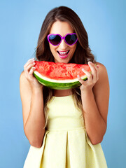 Sticker - Excited, woman and portrait with watermelon in studio for summer snack, confident or smile with nutrition. Gen z model, fruit and sunglasses on blue background for diet, vitamins or healthy food