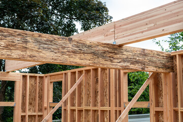 Wall Mural - Closeup detail of new house construction, large glue laminate wood support beam crossing a Parallel Strand Lumber support beam, building framing started with walls and windows
