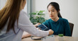 © Johnstocker - Selective focus ,Asian doctor checks blood pressure and gives advice to young female patient in clinic office, Health and medicine consultant
