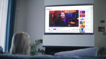 Poster - adult woman watches educational video of blogger about stock trading or investment on the big tv scr