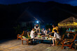 © CandyRetriever  - Group of Young Asian man and woman friends enjoy and fun celebration meeting dinner party eating barbecue grill and drinking beer together on lake house balcony on summer holiday vacation at night.