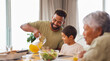 © peopleimages.com - Happy family, dinner and eating food at table together for holiday celebration, bonding or sharing a meal. People, parent or grandparents with kid in dining room for lunch or social gathering in home