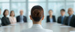 © TH_Stock - A businesswoman with a bun faces a corporate board meeting. Blurred background shows board members in a conference room.