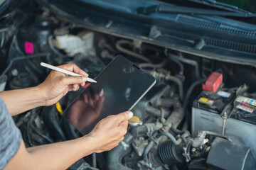 Close-up of Car mechanic noting repair parts during open car hood engine repair unrecognisable man wearing gray glove inspecting car engine and interior of hood of car