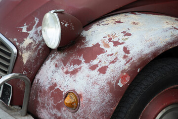 Wall Mural - old car bonnet engine hood wings indicator and headlight of old car used paint worn by time season and sun faded grunge on red burgundy front vehicle