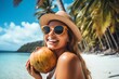© Katerina - a woman holding a coconut on a beach