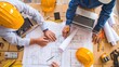 © inthasone - Top view engineers or architects working on blueprints, sketches, and laptop computers office desk. architects team having a showing project plans at site the construction.