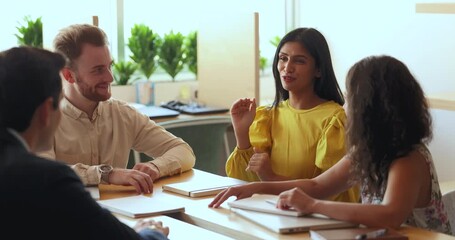 Canvas Print - Positive inspired young Indian project manager woman talking to diverse colleagues at meeting, explaining idea for brainstorming. Multiethnic business team in casual discussing teamwork strategy