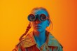© Vladan - A curious young girl wearing stylish goggles poses confidently, showcasing creativity and imagination with vibrant orange and blue hues in the backdrop.