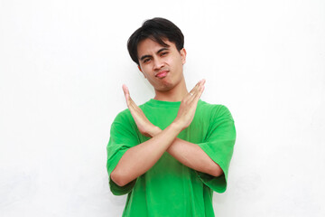 Adult Asian man in green t-shirt posing making no or Stop sign with hand isolated white background