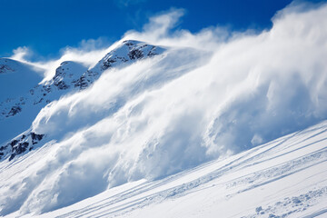 Canvas Print - A massive avalanche of snow cascading down a steep mountain slope with incredible speed, raising clouds of snow dust and showing the sheer force of the avalanche