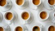 © Shozib - Multiple white espresso coffee cups arranged on a white surface from an aerial perspective