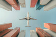 © forenna - Low angle view of an airplane soaring over a sea of vibrant freight containers. Worldwide cargo industry, global shipping, distribution, and delivery logistics. Photo