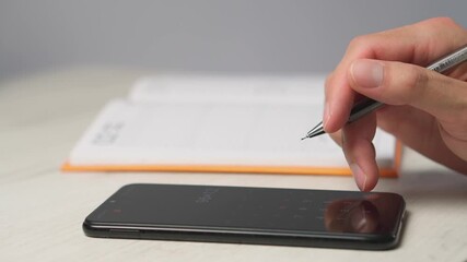 Poster - A person skillfully combines technology with traditional notetaking, writing in a notebook next to a smartphone on a desk. This blend of tools enhances organization and productivity