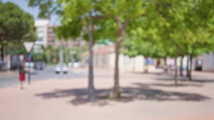 Wall Mural - Outdoor scene with blurred cars trees and sidewalks in a sunny urban area showcasing defocused pedestrians and city buildings in the background