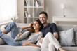 © fizkes - Cheerful wife and husband relax on cozy sofa in modern living room, have fun laughing and joking, enjoy leisure time together, feel love, closeness, share funny memories, relish pleasant conversation