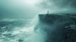 © filmanana - Solitary figure standing on dramatic ocean cliff amidst stormy seas and mist