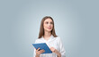 © ImageFlow - Woman holding a tablet with a thoughtful expression in studio.