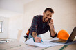 © Drazen - Happy worker talking on the phone while examining housing plans at construction site.