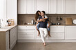 © fizkes - Happy beautiful wife sits on countertop, cuddling husband, smile, enjoy talk, spend time together in good furnished kitchen. New house, bank mortgage for young family, renovation, remodeling services