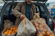 © Milos - An individual in a brown jacket is unloading crates of oranges from the trunk of a vehicle, depicting the activity and effort involved in transporting fresh produce.