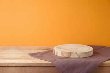 Wall Mural - Empty log podium with tablecloth on wooden table over orange wall background. Halloween mock up for design and product display.