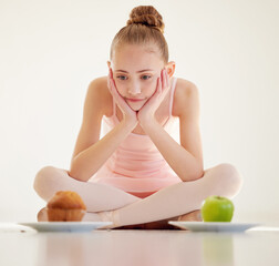 Child, food and choice for health in studio as ballet dancer with muffin, apple and thinking of eating dessert. Doubt, girl and decision with fruit, cupcake and nutrition diet on white background