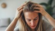 © Zhanna - A focused image of a woman with blonde hair examining her scalp. The image captures the concern over hair thinning, making it suitable for medical, cosmetic, and health-related uses.