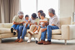 © peopleimages.com - Grandparents, family and children with home, fun and bonding together in lounge with smile. Care, love and support with generations, happy people and young boys on living room sofa with laugh