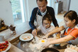 © Maskot - High angle view of girls kneading dough with father in kitchen at home