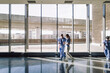 © Maskot - Male and female medical workers walking near glass window at hospital