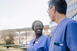 © Maskot - Smiling female healthcare worker talking with male colleague outside hospital building