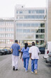 © Maskot - Rear view of male and female medical experts walking towards hospital building