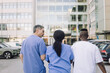 © Maskot - Rear view of male and female healthcare workers discussing while walking towards hospital building