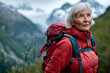© Wanida - A woman wearing a red jacket and backpack is standing on a mountain