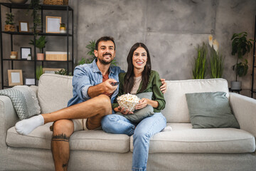 Wall Mural - adult couple watch movie, series on television and eat popcorn at home