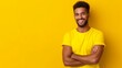 © Nataliia_Trushchenko - A man in a yellow shirt is smiling and standing with his arms crossed. The image has a bright and cheerful mood, with the yellow background and the man's happy expression