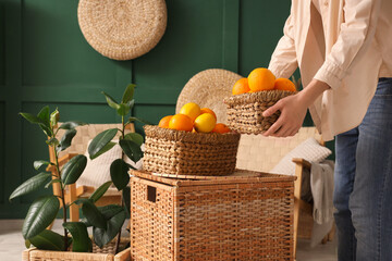 Sticker - Young woman holding wicker basket with citruses in green living room