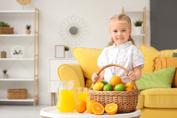 Poster - Cute little girl with basket of citrus fruits and juice on table at home