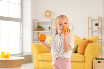 Wall Mural - Cute little girl eating oranges at home