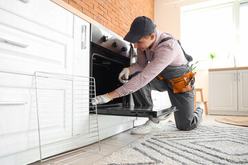 Wall Mural - Male technician repairing electric oven in kitchen